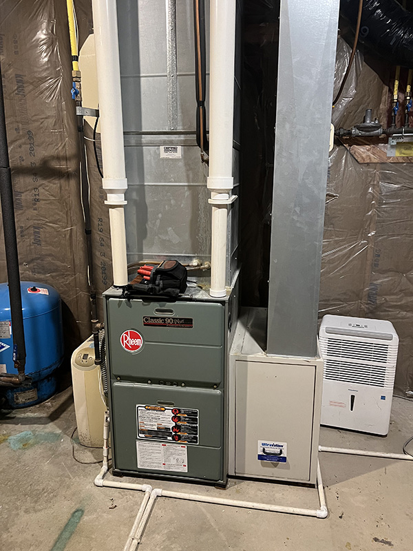 High-efficiency gas furnace installed with PVC venting and ductwork in a residential basement