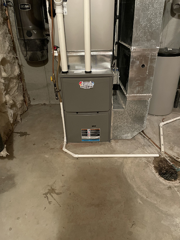 High-efficiency gas furnace installed in a residential basement with ductwork and PVC venting